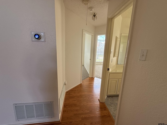 2414 Stillwater Dr, Mesquite, TX 75181 - hall featuring a textured wall, wood finished floors, and a textured ceiling