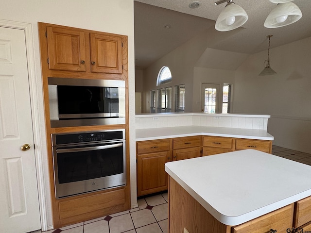 2414 Stillwater Dr, Mesquite, TX 75181 - kitchen featuring stainless steel appliances, light countertops, a peninsula, brown cabinets, and light tile patterned floors