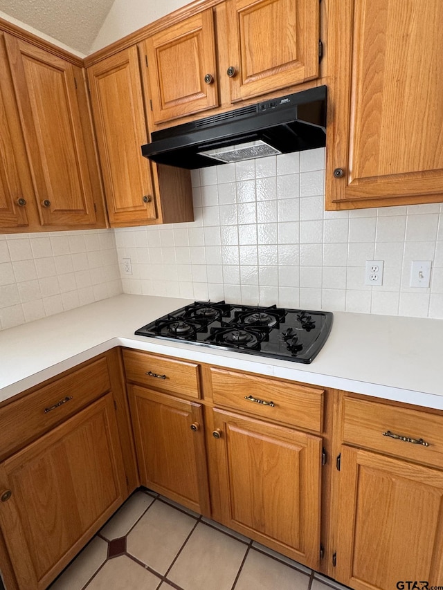 2414 Stillwater Dr, Mesquite, TX 75181 - kitchen with black gas cooktop, under cabinet range hood, brown cabinetry, light countertops, and backsplash