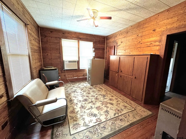 sitting room featuring hardwood / wood-style floors, ceiling fan, wooden walls, and cooling unit