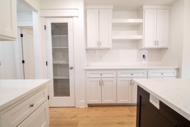 kitchen with light stone counters, tasteful backsplash, light hardwood / wood-style flooring, and white cabinets