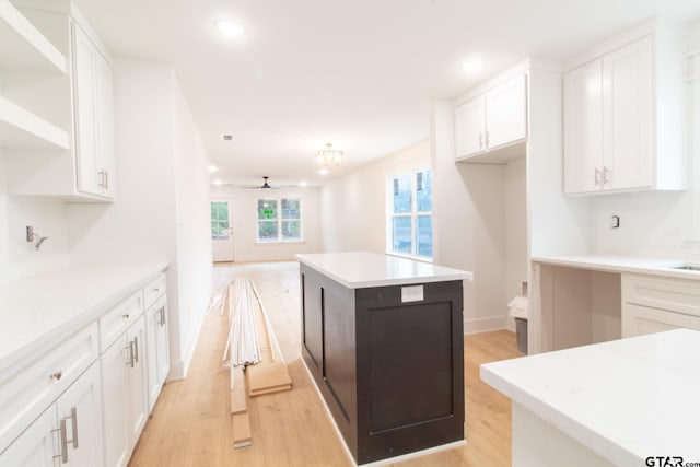 kitchen featuring ceiling fan, a center island, white cabinets, and light wood-type flooring