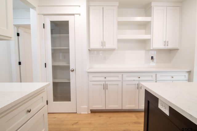 kitchen featuring white cabinetry, tasteful backsplash, light stone countertops, and light hardwood / wood-style floors