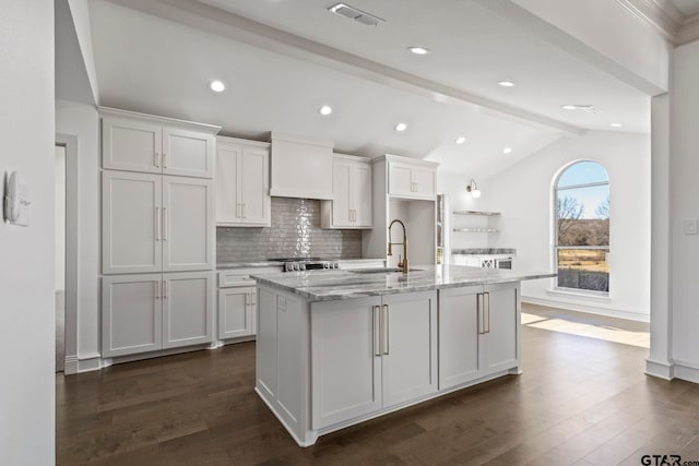 kitchen featuring white cabinetry, sink, and an island with sink