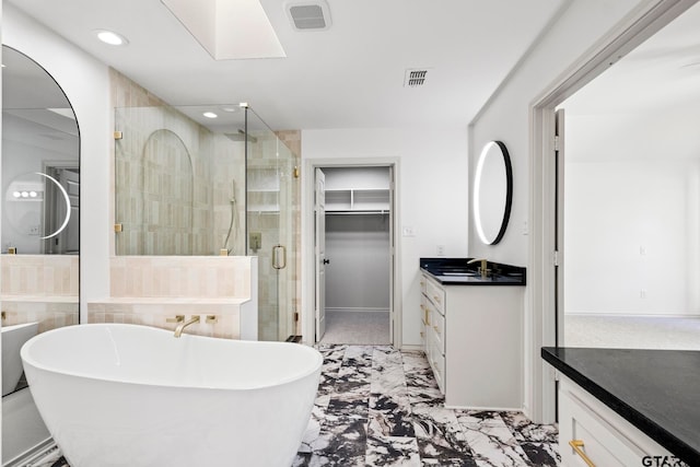 bathroom with vanity, shower with separate bathtub, and a skylight