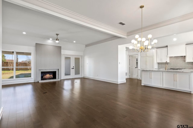 unfurnished living room featuring a brick fireplace, ceiling fan with notable chandelier, dark hardwood / wood-style floors, and ornamental molding