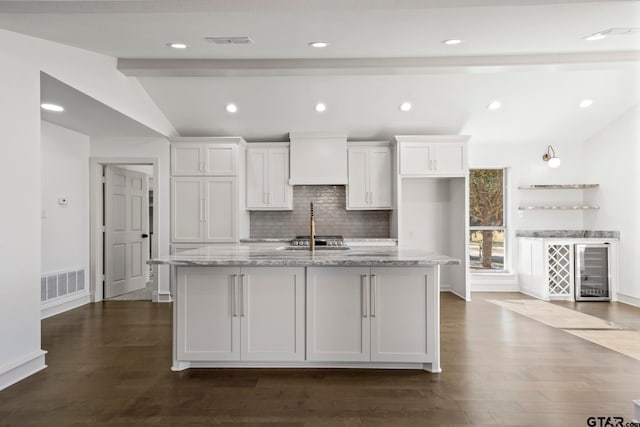 kitchen with white cabinetry, a kitchen island with sink, and light stone counters