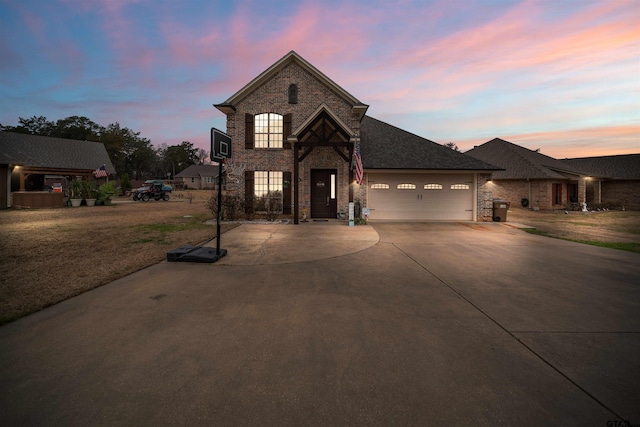 view of front of home with a garage, concrete driveway, brick siding, and a lawn