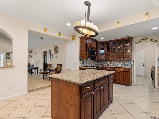 kitchen with a kitchen island, stainless steel appliances, hanging light fixtures, and dark brown cabinets