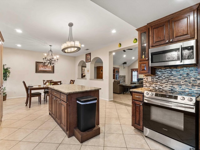 kitchen featuring tasteful backsplash, stainless steel appliances, light stone counters, a center island, and light tile patterned floors