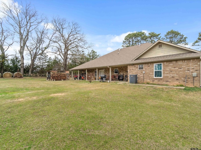 back of house with central AC unit and a lawn