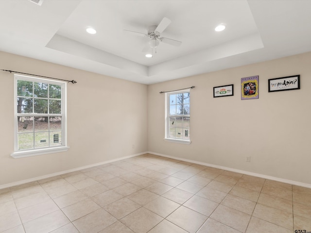 spare room with a tray ceiling, ceiling fan, and light tile patterned floors