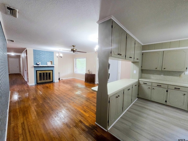 3008 Oak Knob Dr, Tyler, TX 75701 - kitchen featuring wood-type flooring, ceiling fan, light countertops, a fireplace, and a textured ceiling