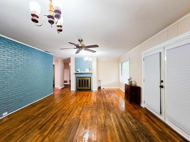3008 Oak Knob Dr, Tyler, TX 75701 - unfurnished living room with brick wall, a chandelier, wood-type flooring, ceiling fan, and a fireplace
