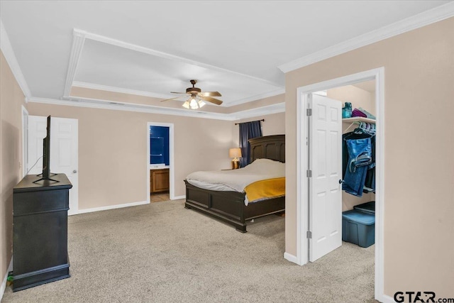 carpeted bedroom with ensuite bathroom, ceiling fan, a raised ceiling, and crown molding