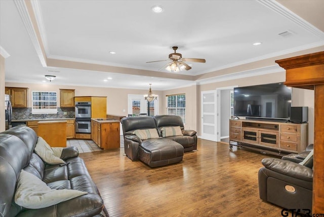 living room with ornamental molding, sink, light hardwood / wood-style floors, and ceiling fan with notable chandelier