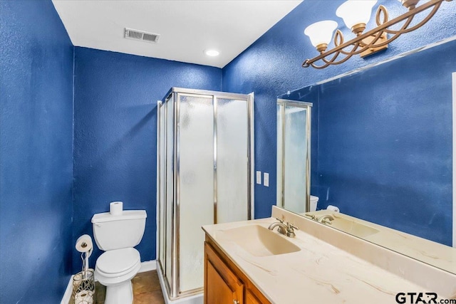 bathroom featuring toilet, vanity, an enclosed shower, and tile patterned floors