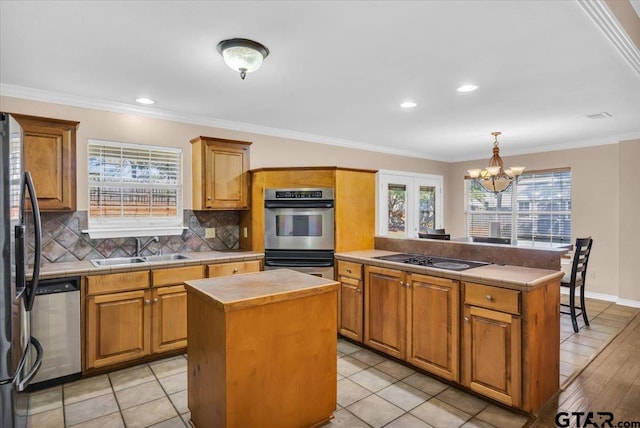 kitchen featuring a kitchen island, appliances with stainless steel finishes, sink, and ornamental molding