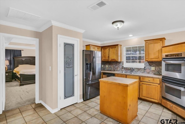 kitchen featuring stainless steel appliances, sink, light tile patterned floors, crown molding, and a kitchen island