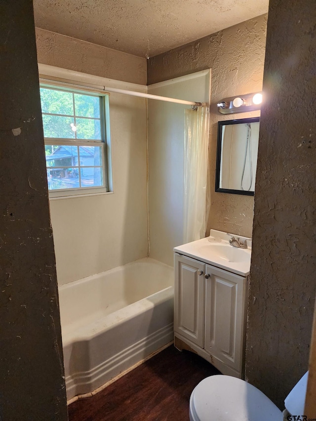 full bath with shower / bathtub combination with curtain, a textured wall, wood finished floors, toilet, and vanity
