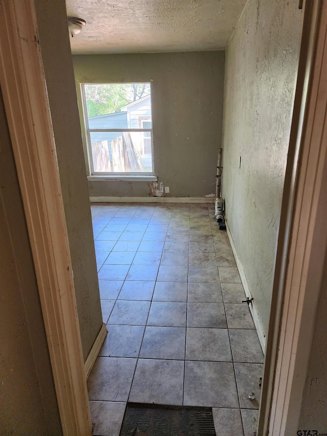 corridor featuring tile patterned floors and a textured ceiling