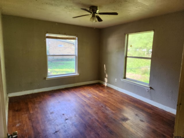 empty room with plenty of natural light, baseboards, wood finished floors, and ceiling fan