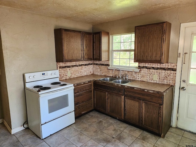 kitchen with light tile patterned floors, decorative backsplash, a sink, and electric stove