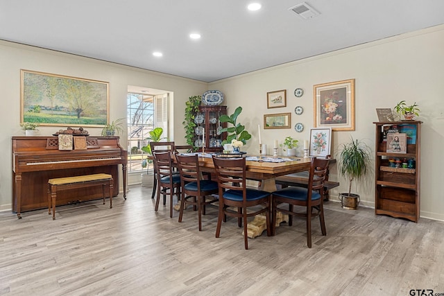 dining room with crown molding and light wood-type flooring