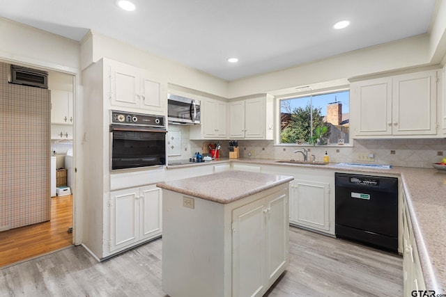 kitchen featuring sink, black appliances, a center island, light hardwood / wood-style floors, and white cabinets