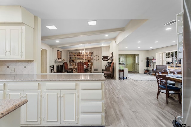 kitchen featuring backsplash, beam ceiling, light stone countertops, white cabinets, and light wood-type flooring