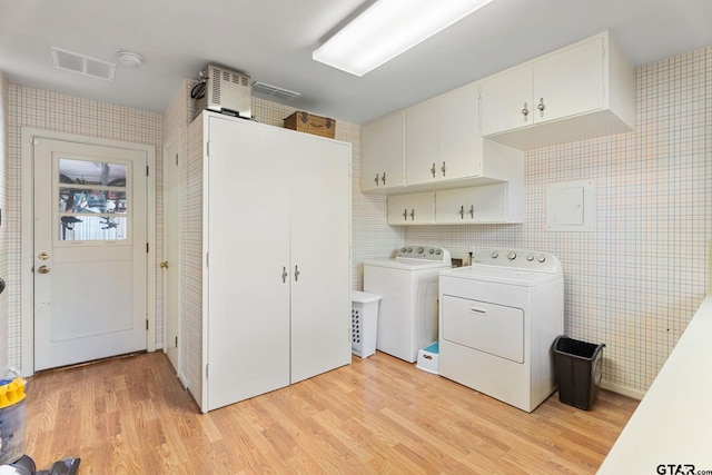 laundry area featuring independent washer and dryer, cabinets, and light hardwood / wood-style floors