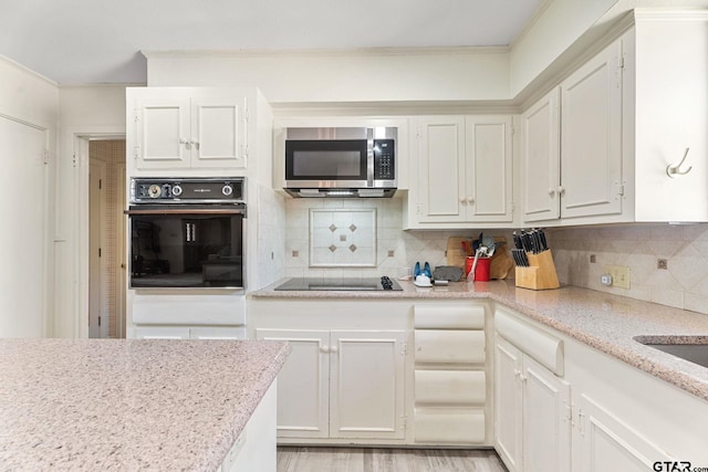 kitchen featuring crown molding, tasteful backsplash, light stone counters, black appliances, and white cabinets