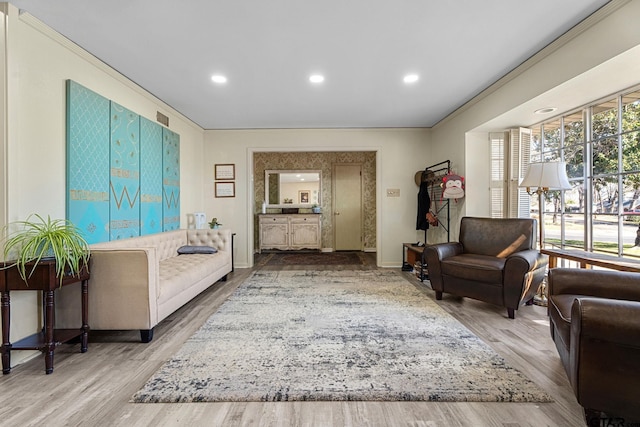 living room with crown molding, plenty of natural light, and light hardwood / wood-style flooring