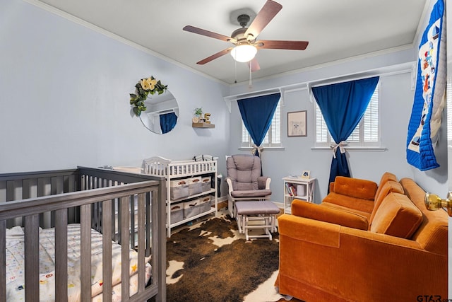 carpeted bedroom with crown molding, a nursery area, and ceiling fan