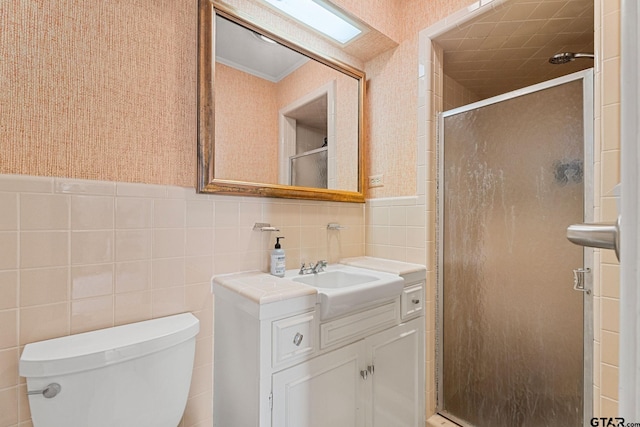 bathroom with vanity, toilet, tile walls, and a shower with shower door