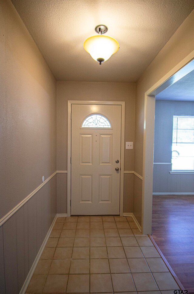 doorway to outside with light wood-type flooring and a textured ceiling