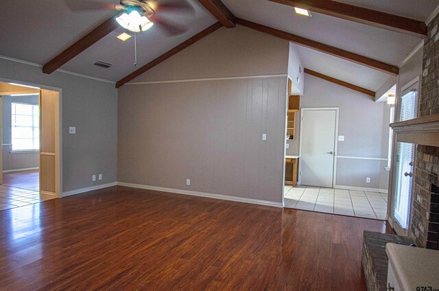 unfurnished living room featuring ceiling fan, wood-type flooring, vaulted ceiling with beams, and a brick fireplace