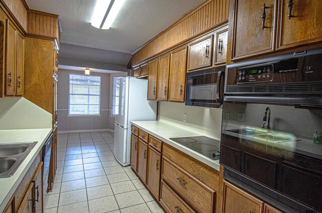 kitchen with black appliances, a textured ceiling, and light tile patterned floors