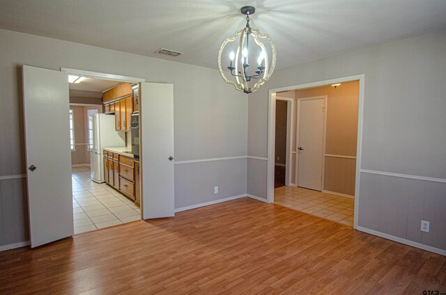 unfurnished room with light hardwood / wood-style floors and a notable chandelier