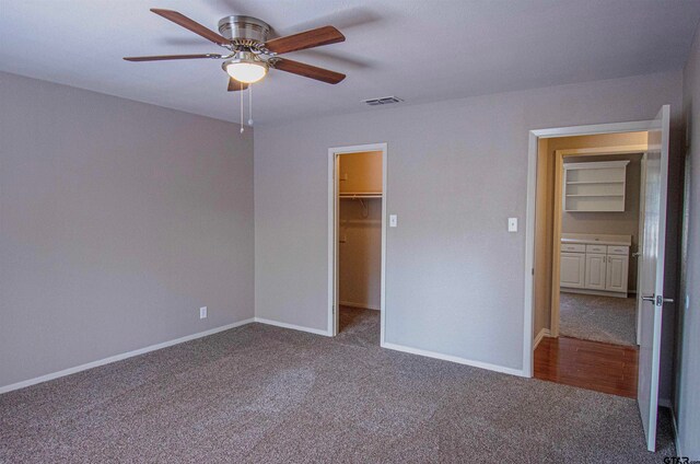 unfurnished bedroom with ceiling fan, carpet flooring, a closet, and a walk in closet