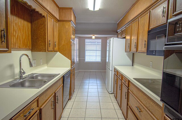 kitchen with light tile patterned floors, a textured ceiling, sink, and black appliances