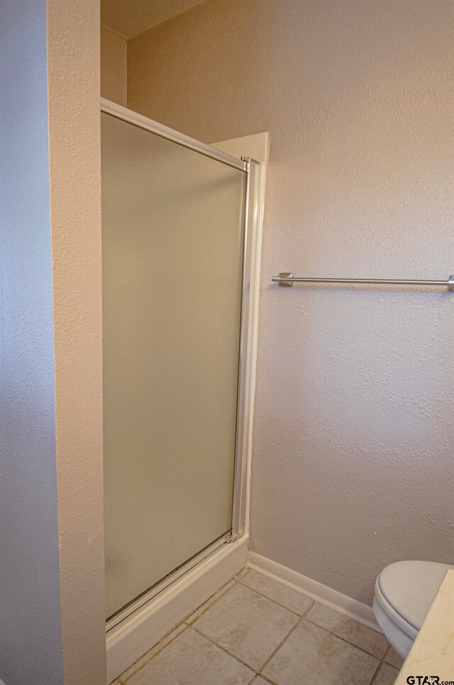 bathroom with toilet, tile patterned floors, and a shower with door