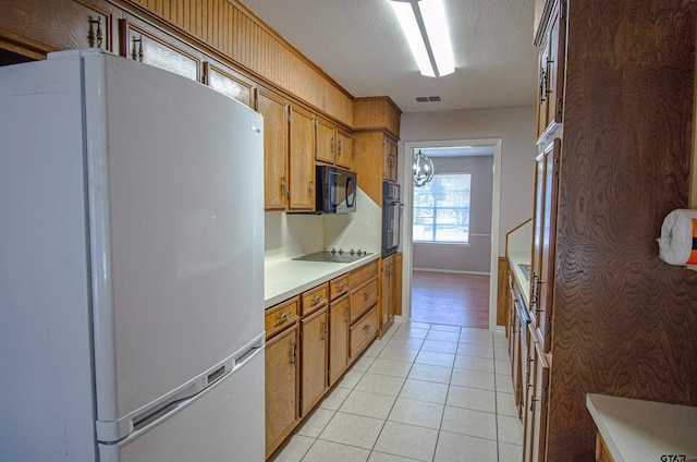 kitchen featuring a textured ceiling, black appliances, and light tile patterned floors