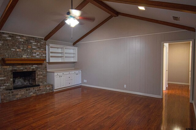 unfurnished living room with dark wood-type flooring, ceiling fan, a fireplace, and lofted ceiling with beams