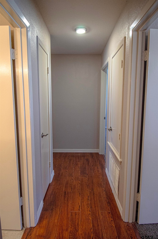 hall featuring a textured ceiling and dark hardwood / wood-style flooring