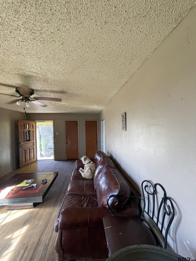 living room with a textured ceiling, hardwood / wood-style flooring, and ceiling fan