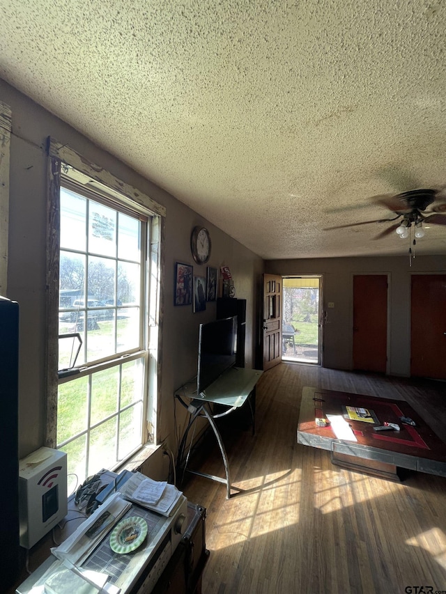 living room featuring a textured ceiling, hardwood / wood-style flooring, and ceiling fan