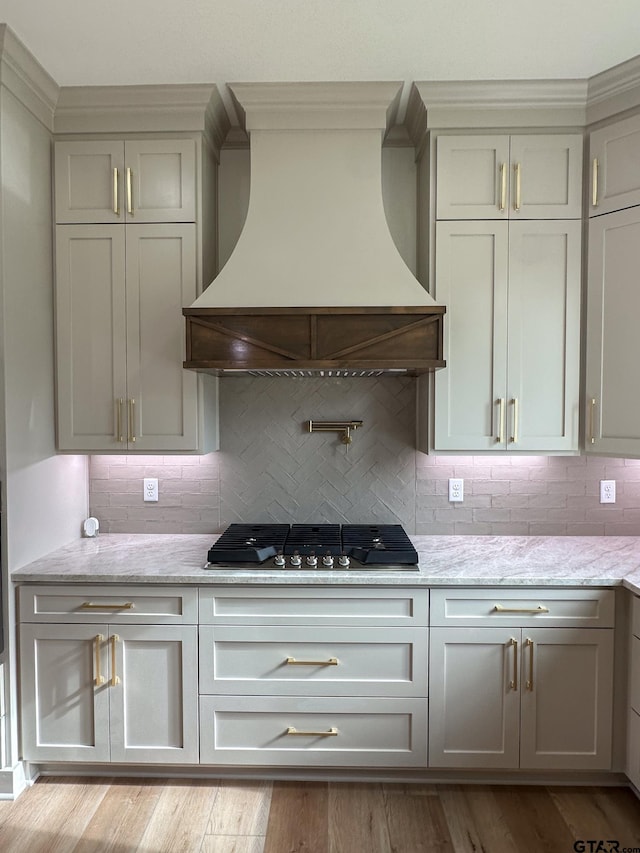 14438 Woodland Crk, Tyler, TX 75706 - kitchen with premium range hood, gas stovetop, decorative backsplash, light stone counters, and light wood-style flooring