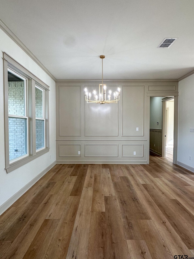 14438 Woodland Crk, Tyler, TX 75706 - unfurnished dining area featuring a chandelier, light wood-style flooring, a decorative wall, and ornamental molding