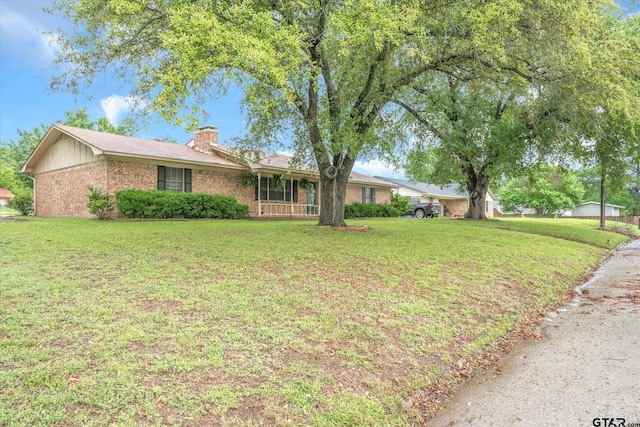 ranch-style house featuring covered porch and a front yard